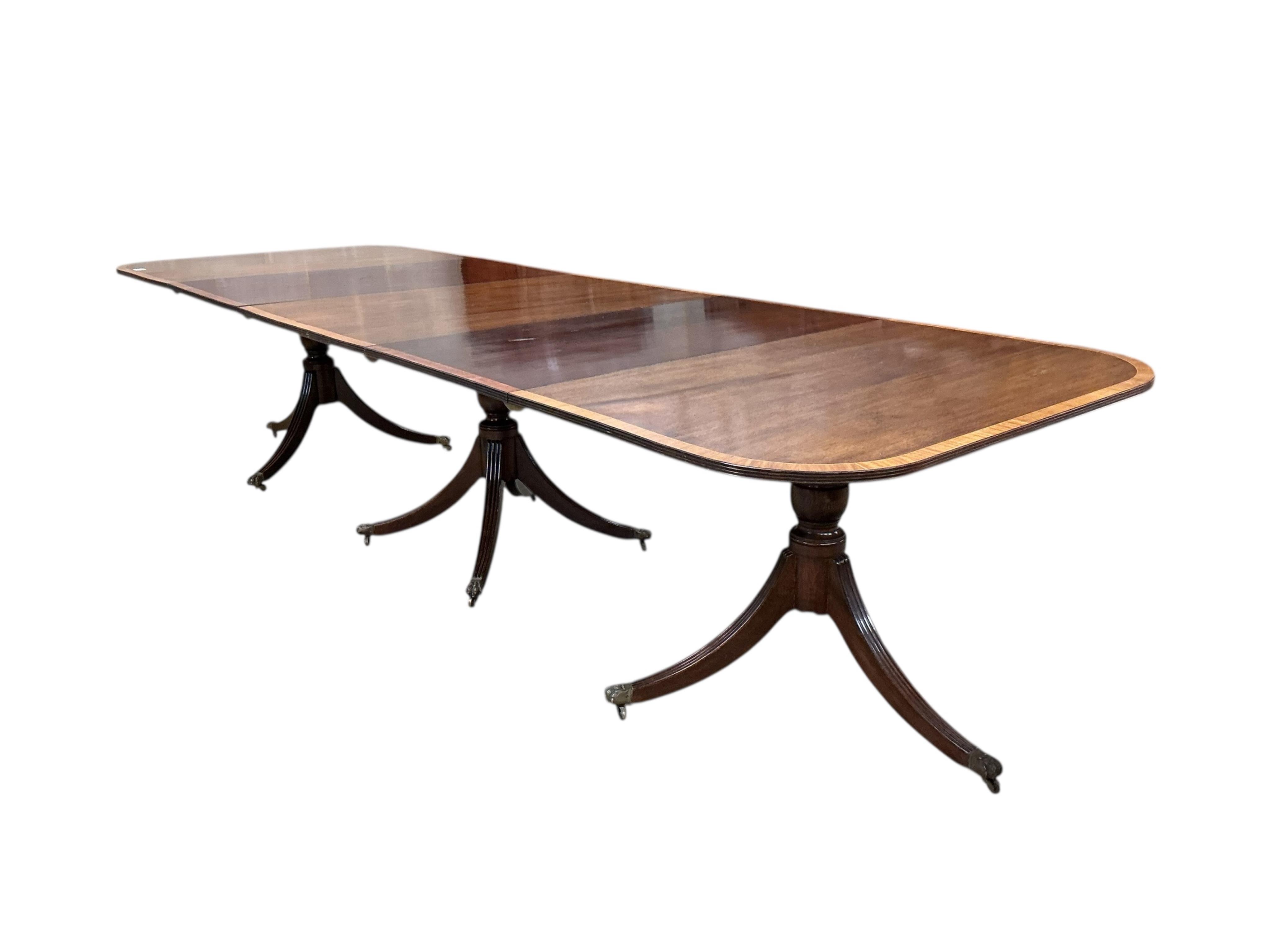 A Regency style mahogany and satinwood banded three pillar dining table, width 320cm extended, two spare leaves, depth 114cm, height 74cm